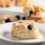 blueberry biscuits on white plate with other biscuits in background