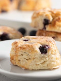 blueberry biscuits on white plate with other biscuits in background