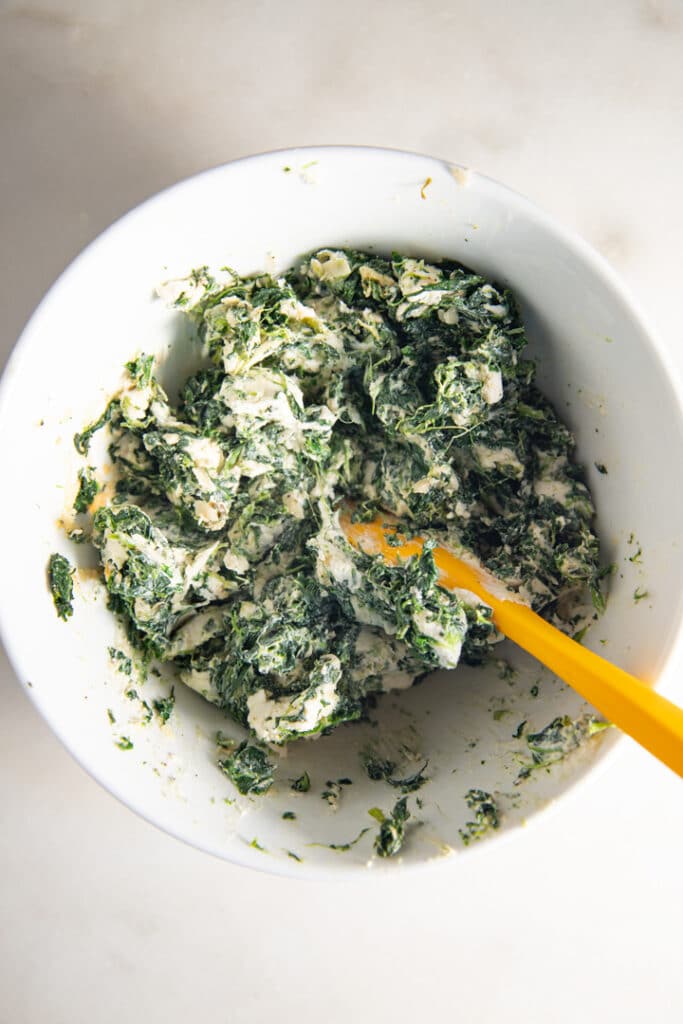 Mixing the spinach and cream cheese together in a bowl