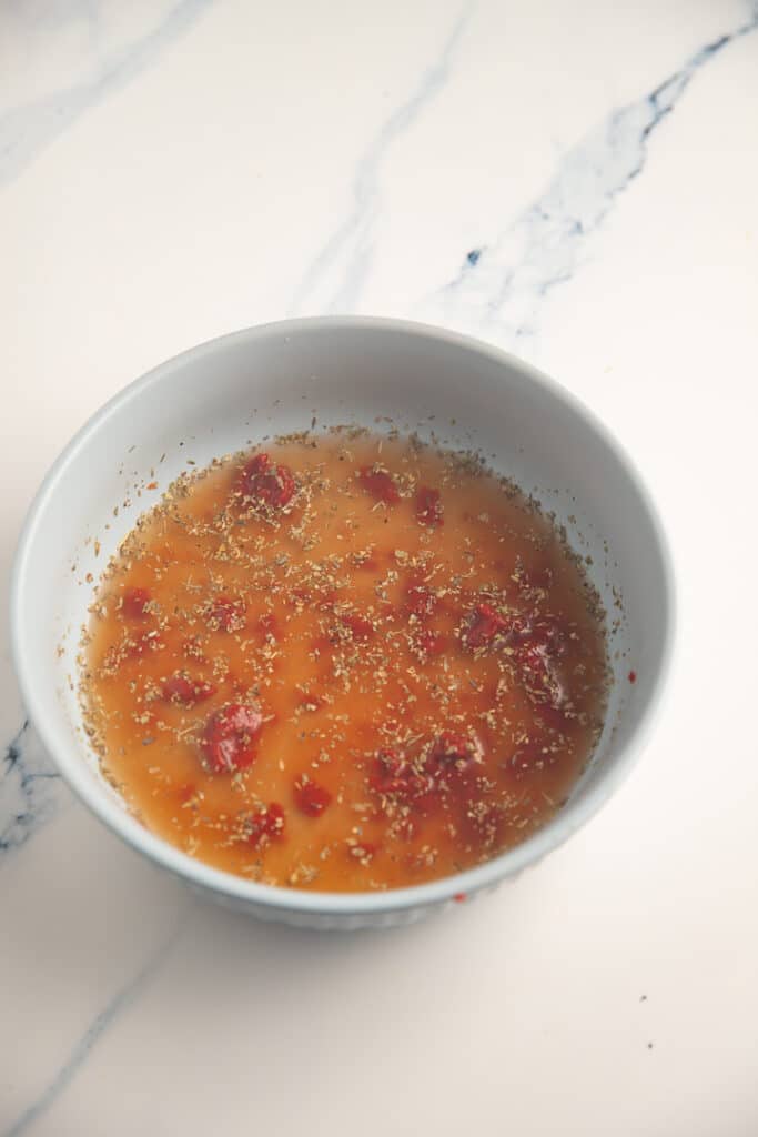 Tomato paste and chicken broth mixed together in a bowl