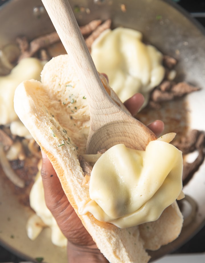 Placing the cheesesteak into a roll