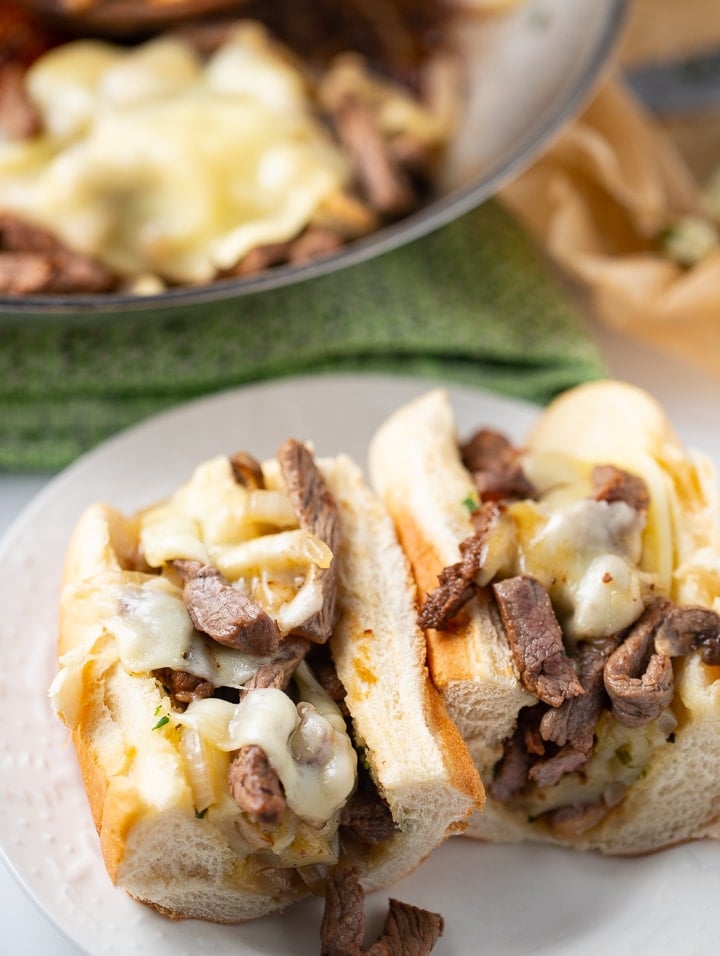 Overhead shot of two cheesesteak sandwiches on a plate