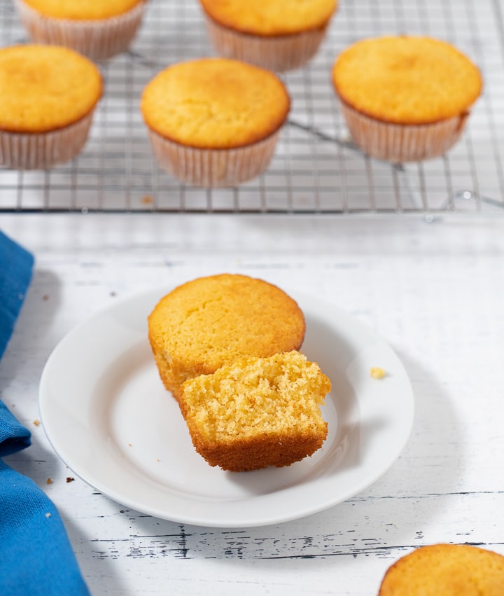 A cornbread muffin broken in half on a white plate