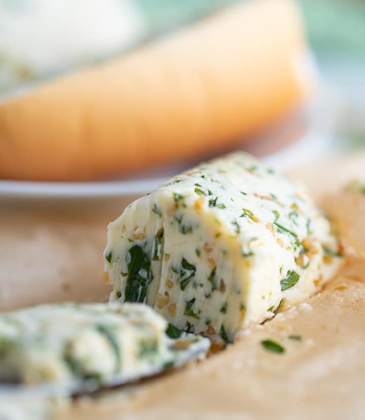 Close up of the end of the garlic herb butter cut off with a knife