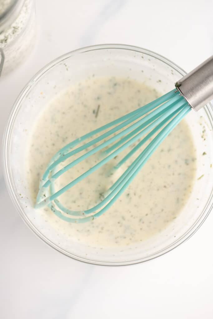 Whisking the ranch seasoning with water and mayonnaise to make a sauce