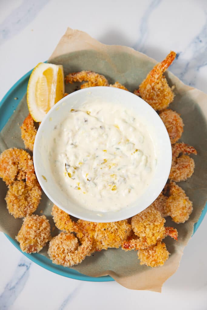 Tartar sauce in a bowl in the middle of a plate of shrimp