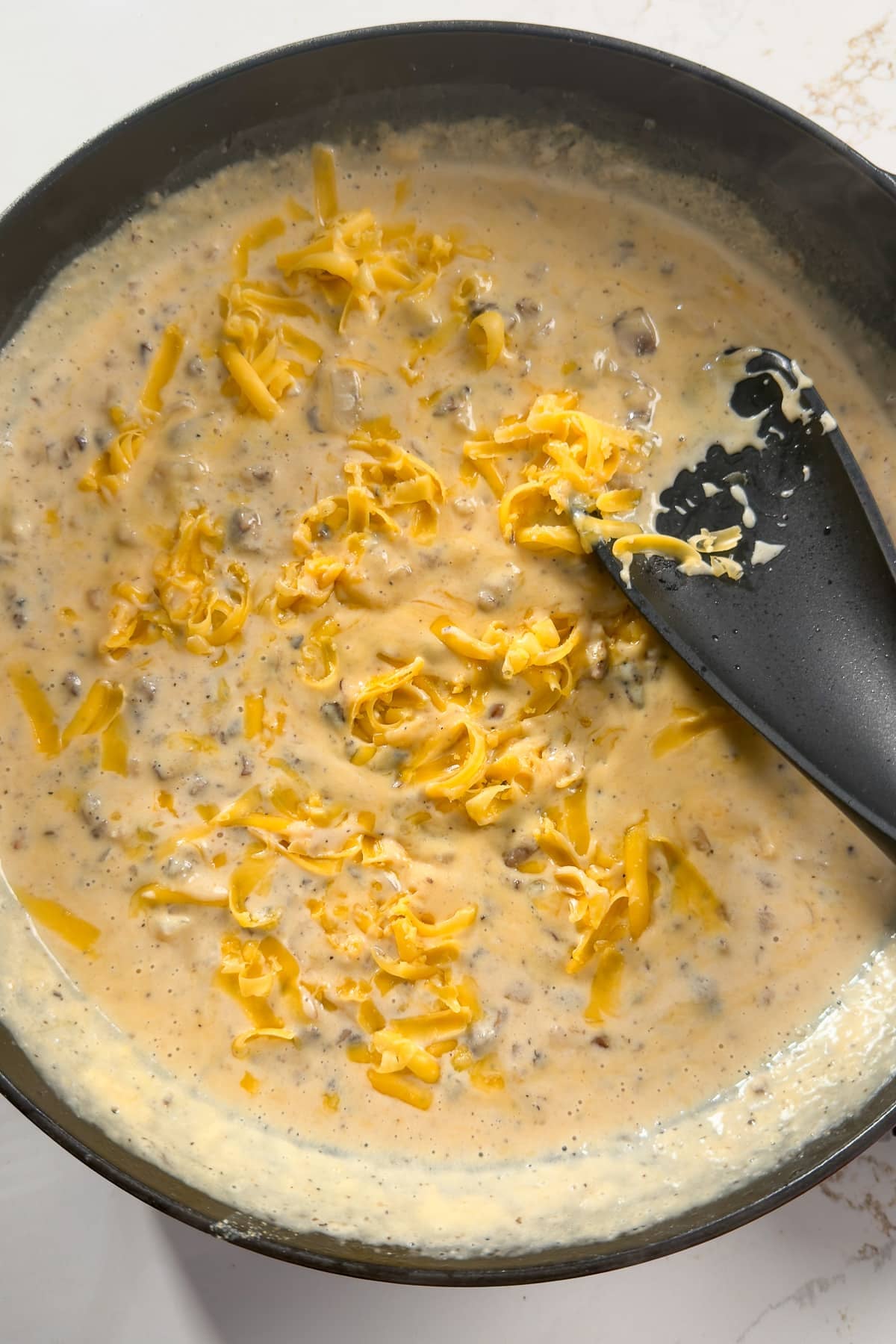 cheese being mixed into cream sauce