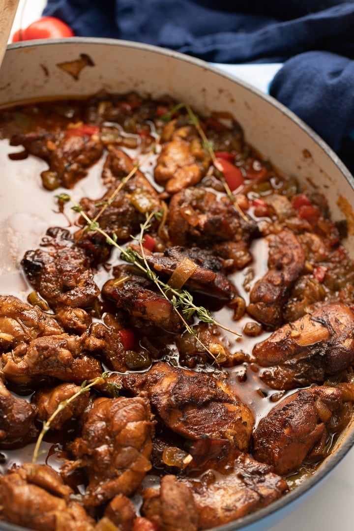brown stew chicken in pot with blue towel behind it