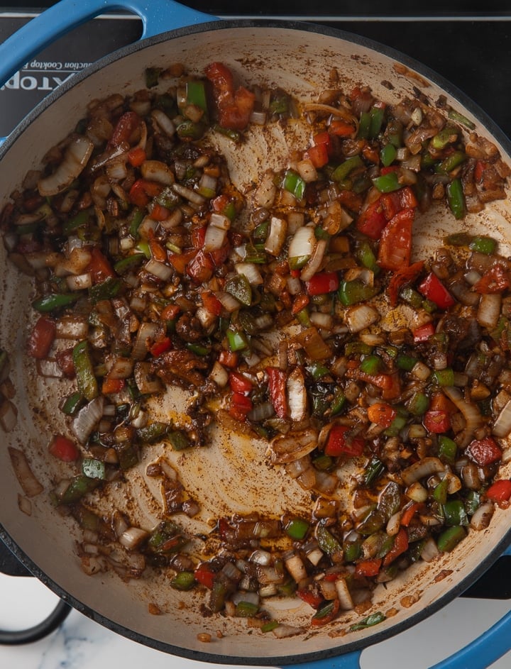 peppers and onions being browned in pan