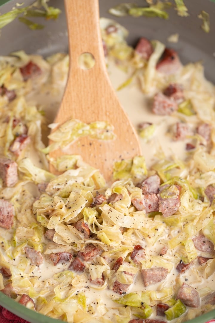 cabbage in skillet with wooden spoon sticking out