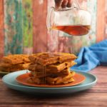 Maple syrup being poured over the pumpkin waffles