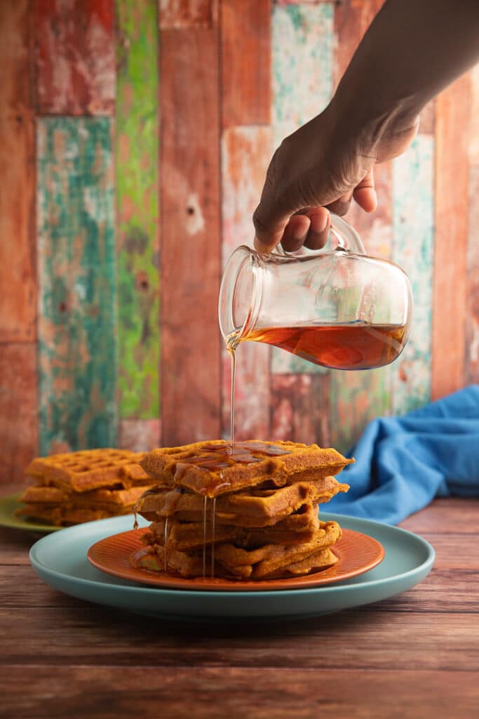 Pouring syrup over stacked waffles