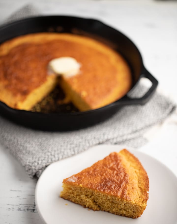 The cornbread in a skillet and a sliced served on a plate