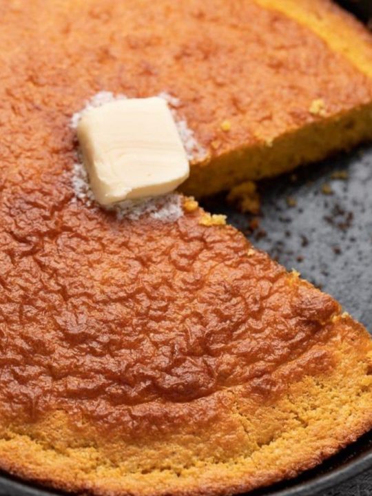 cornbread with slice cut from it and butter on top