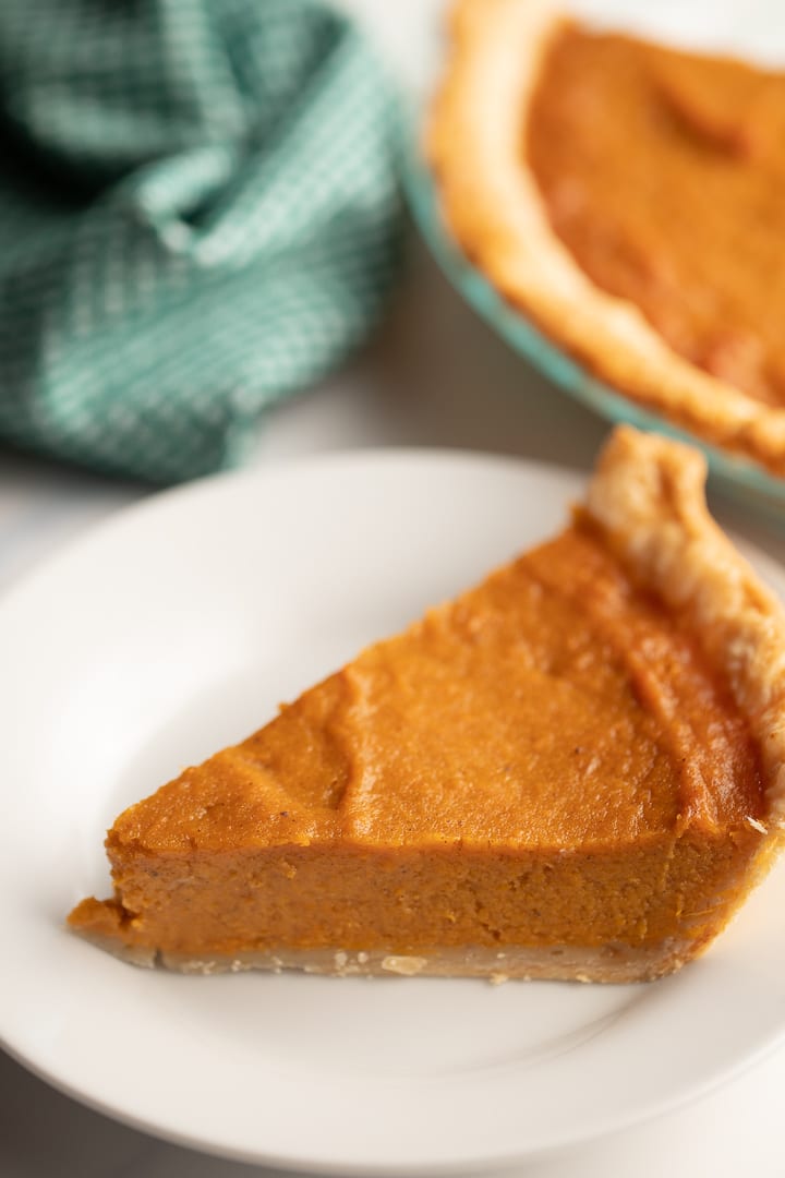 southern sweet potato pie on white plate with pie in background
