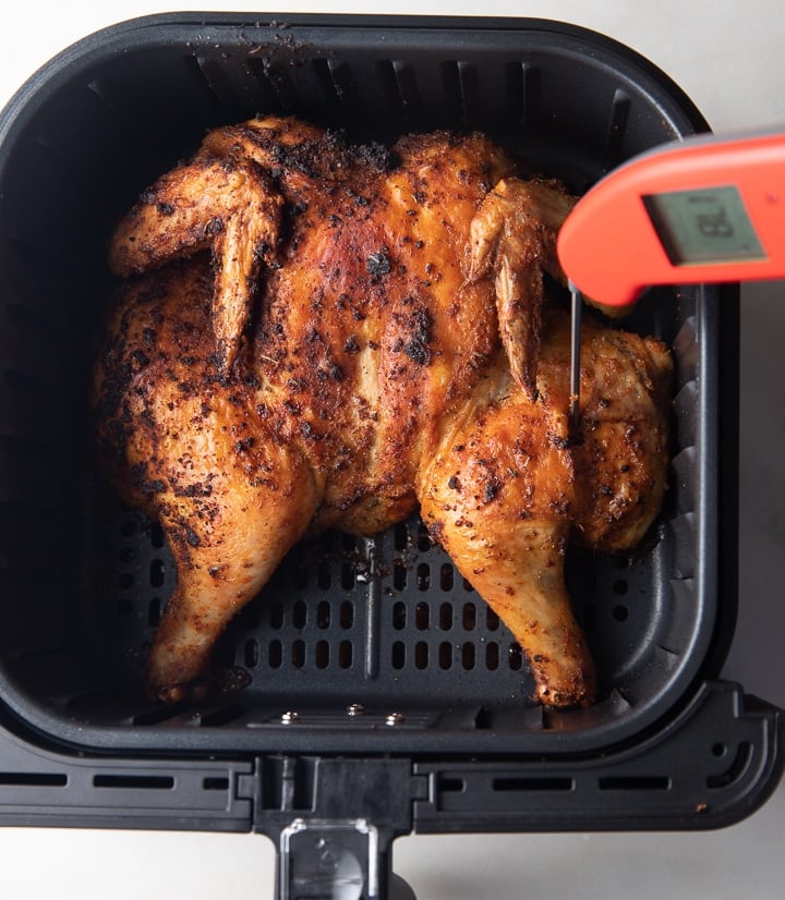 Using an instant read thermometer to check if the chicken is cooked