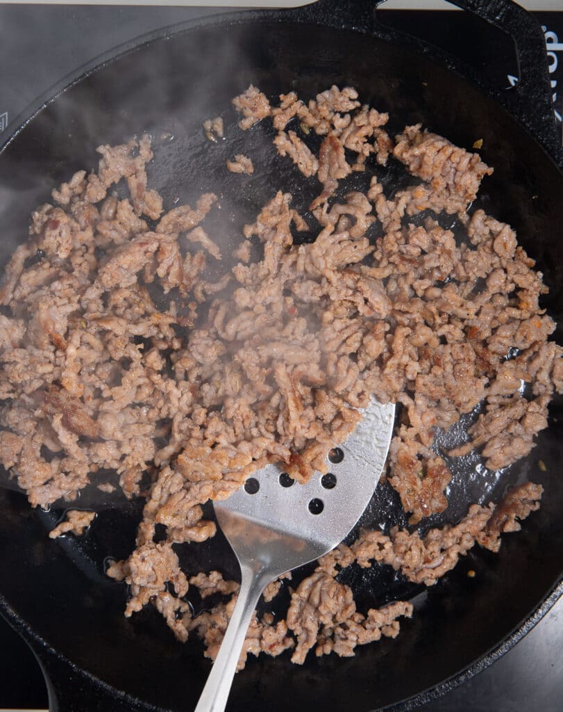 Browning the sausage in a skillet.