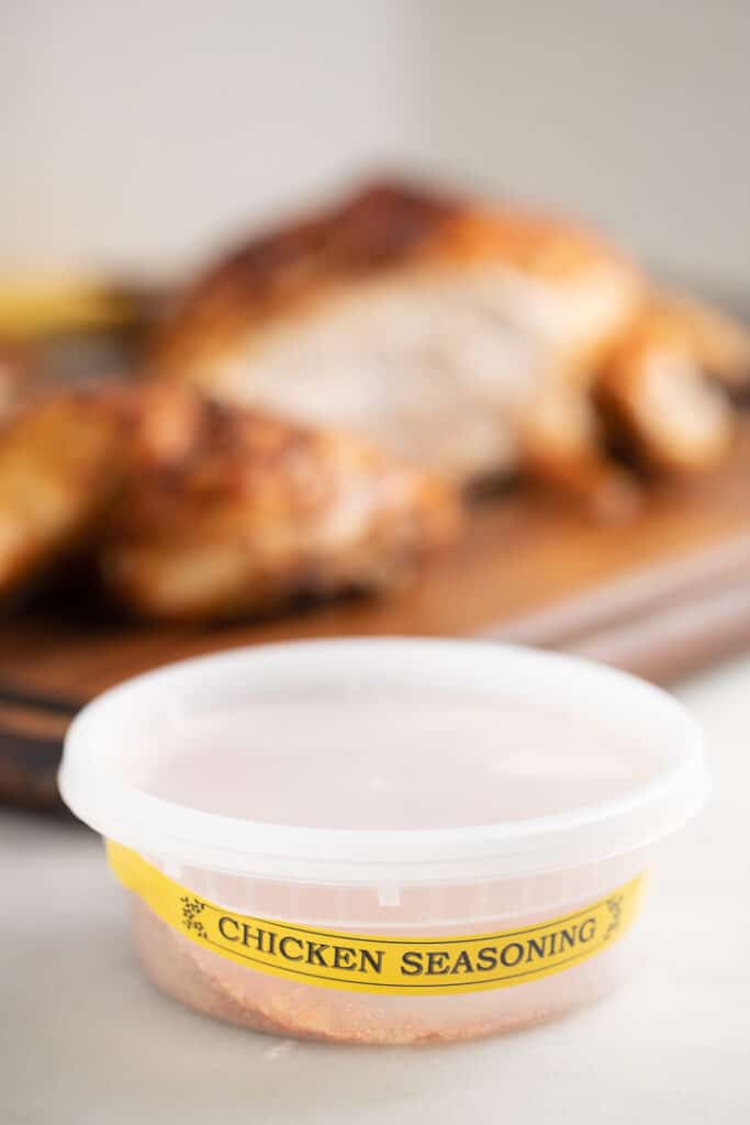 Chicken seasoning in front of a cooked spatchcock chicken