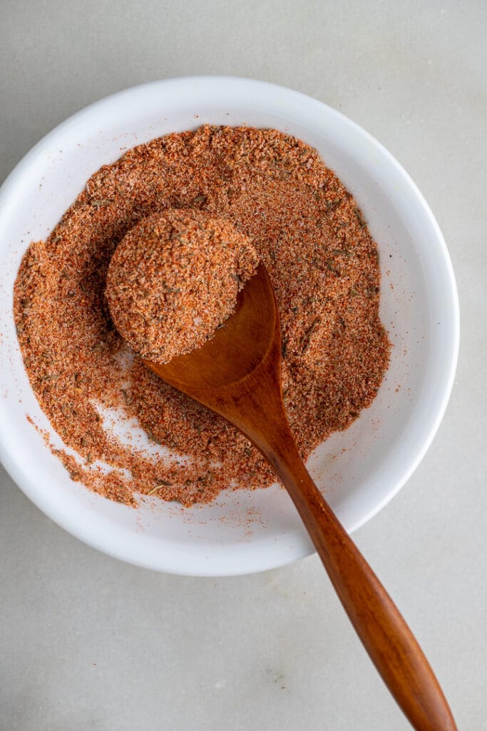 Chicken seasoning in a white bowl with a spoon