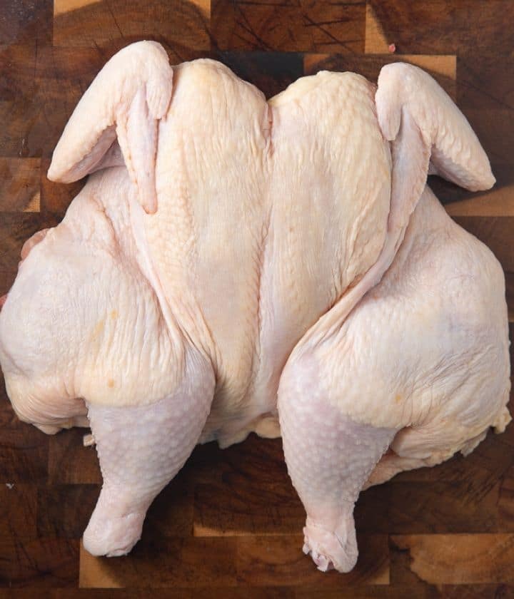 a spatchcocked chicken on a wooden board