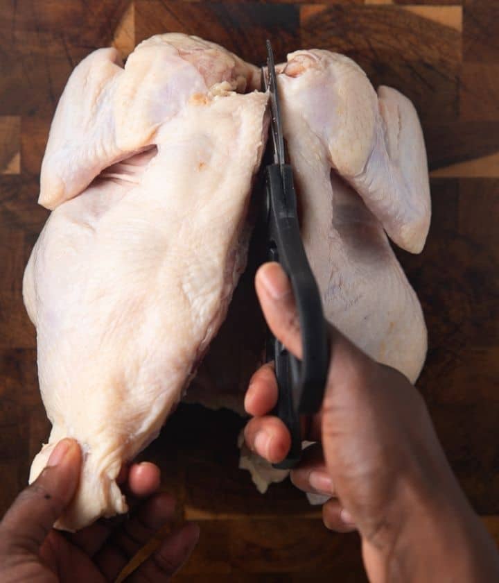 scissors cutting along the backbone of a whole chicken