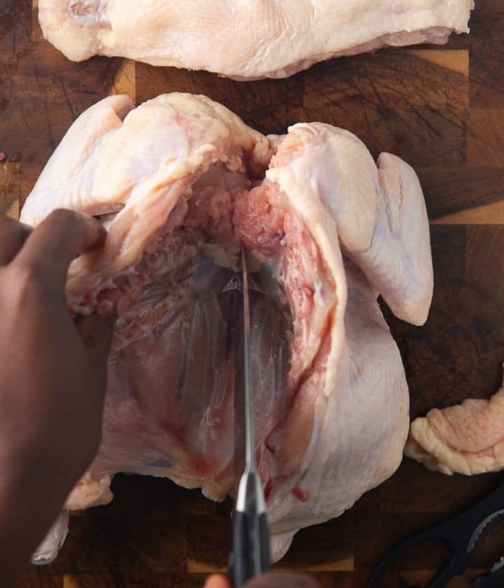 a knife cutting the cartilage of the chicken between the chicken breast