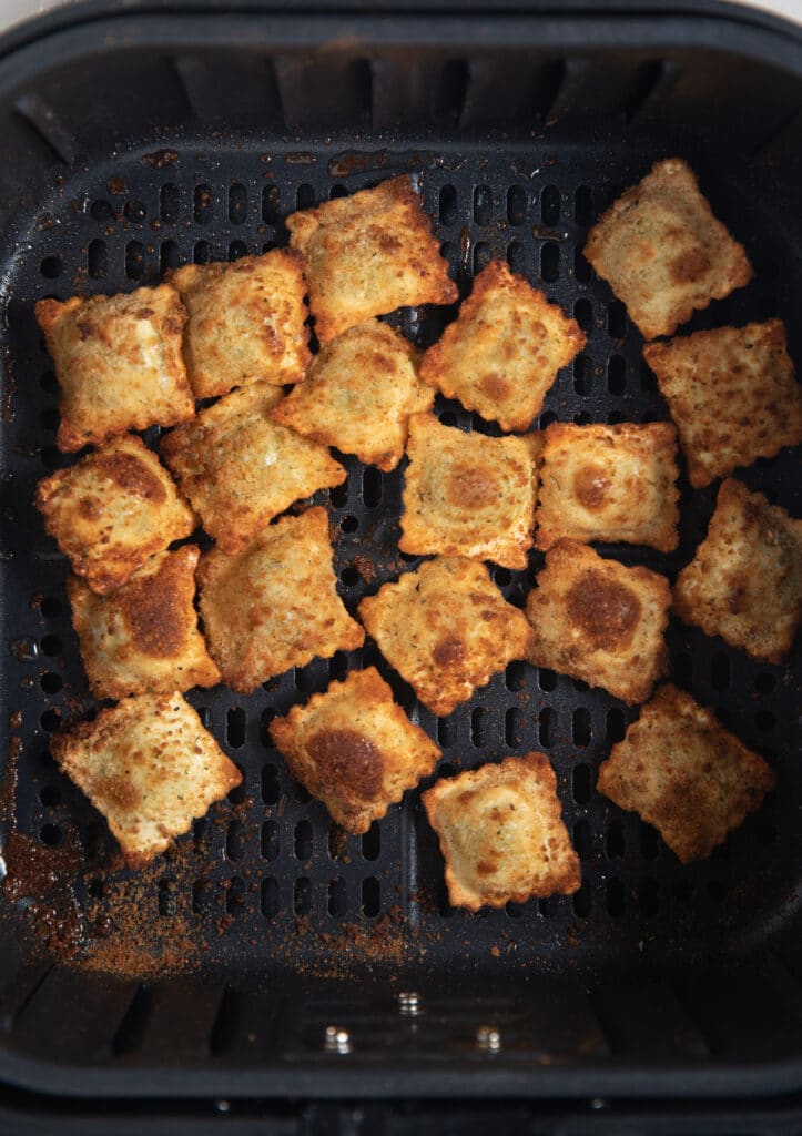 The cooked ravioli in the air fryer basket.