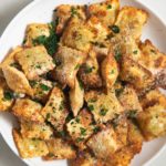 Air fried toasted ravioli on a white plate.