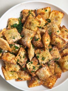 Air fried toasted ravioli on a white plate.