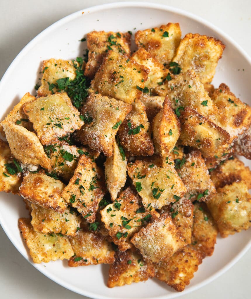 Air fried toasted ravioli on a white plate.