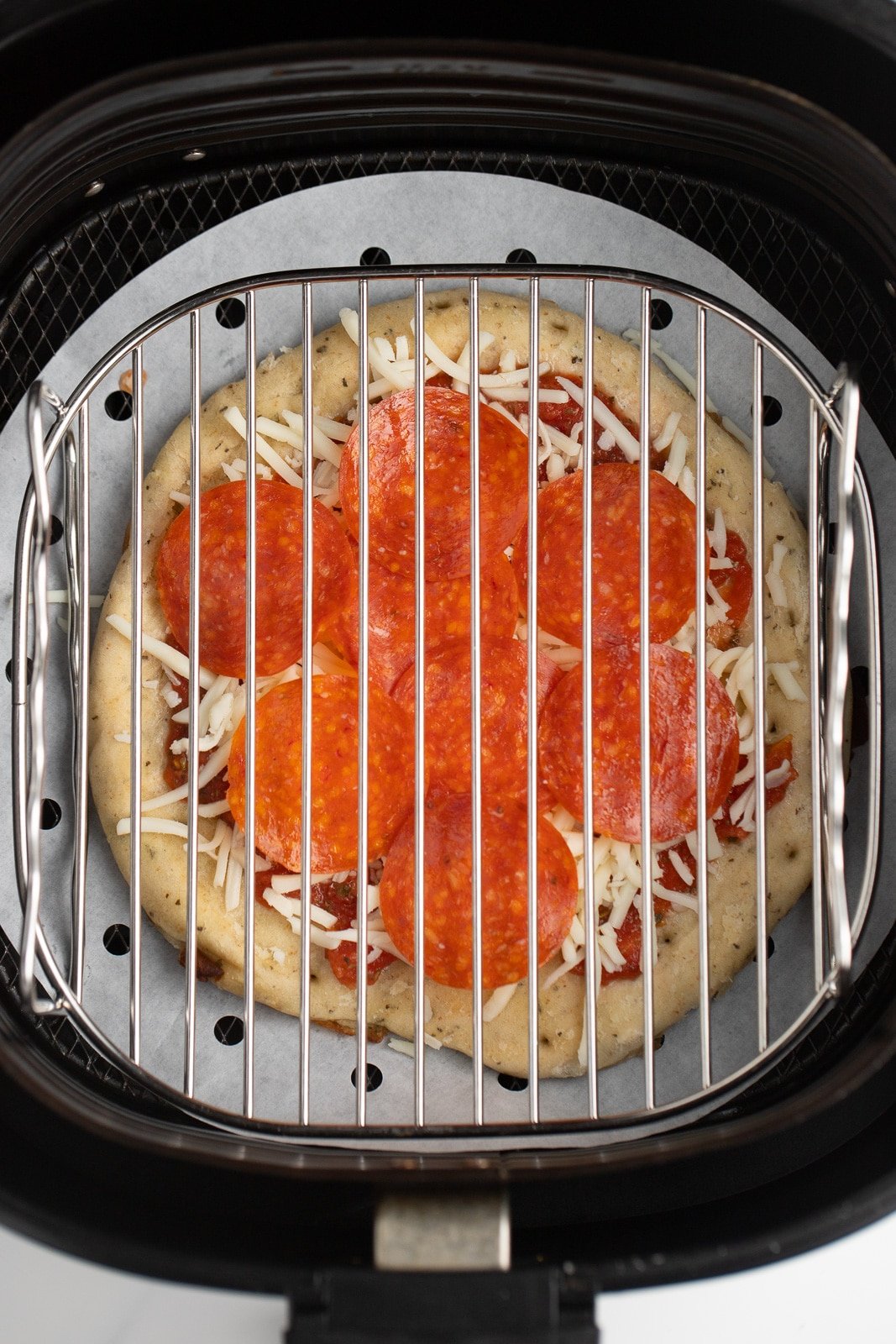 The uncooked pizza in the air fryer basket.