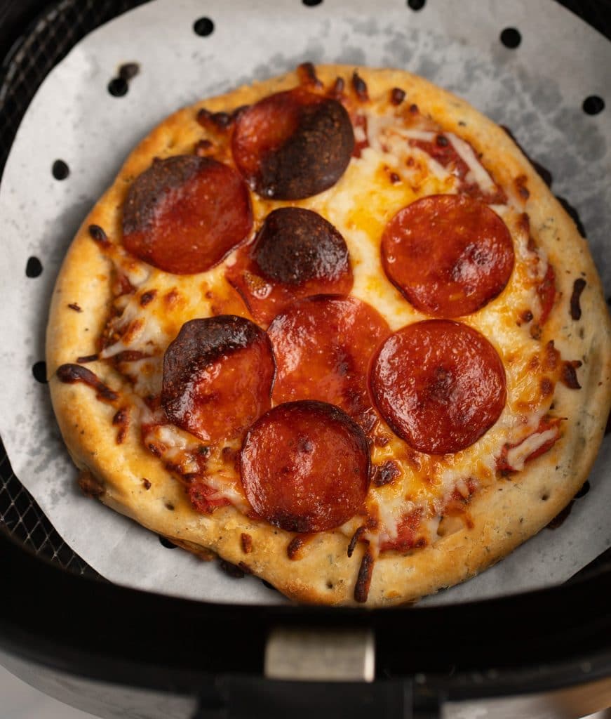 The cooked pizza in the air fryer basket.