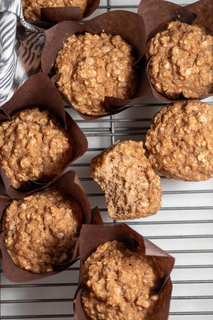 Seven applesauce muffins on a wire rack.