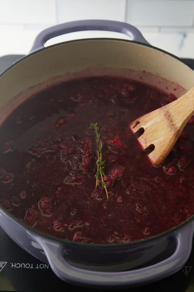 Stirring in the broth, thyme and beans with a wooden spatula.