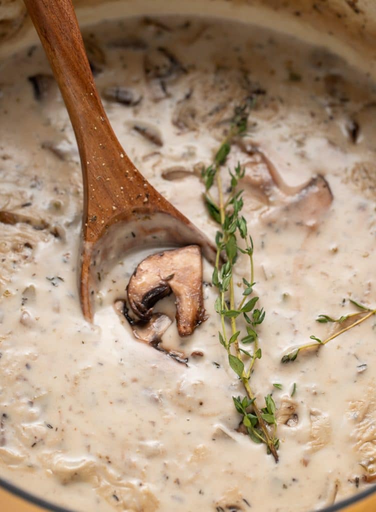 A wooden spoon in a pot of cream of mushroom soup.