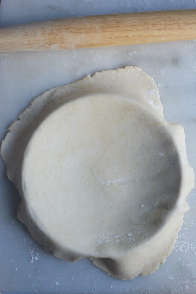 Laing the dough over the pie dish.