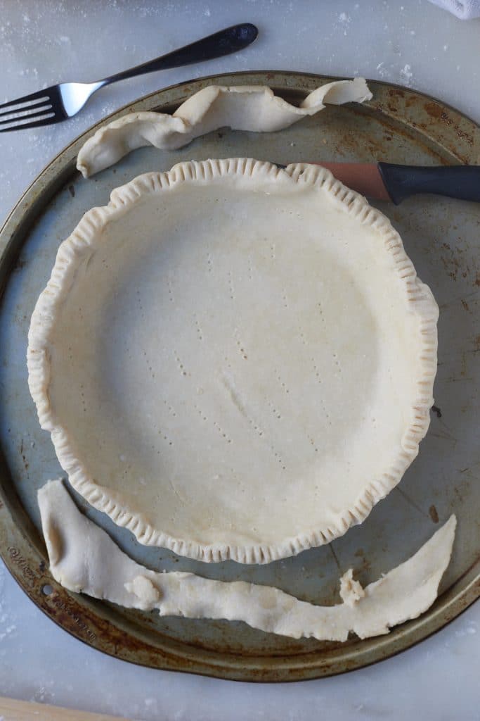Trimming the excess dough away from the pie tin.