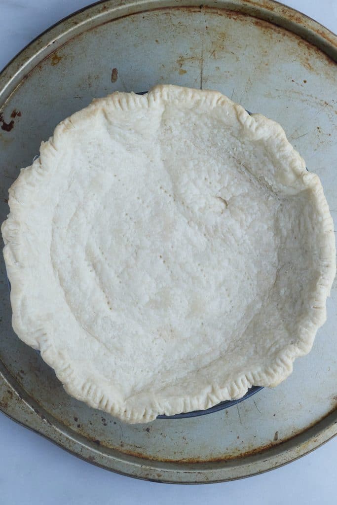 The part baked pie crust on a metal baking sheet.