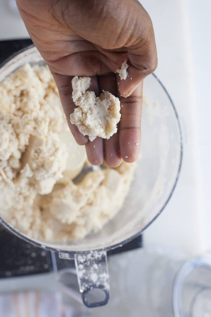 A hand holding a piece of the pie dough.