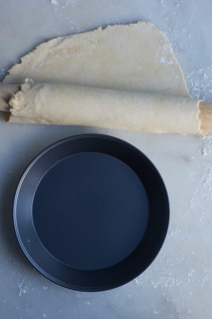 The dough being rolled over a rolling pin.