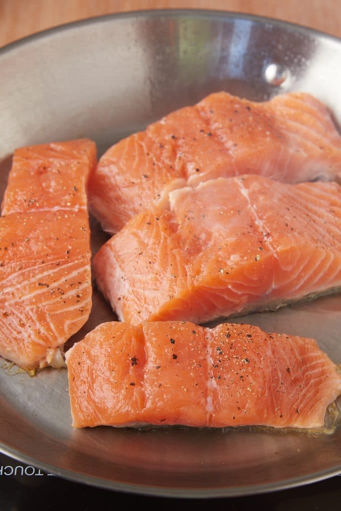 Raw salmon skin side down in a pan.