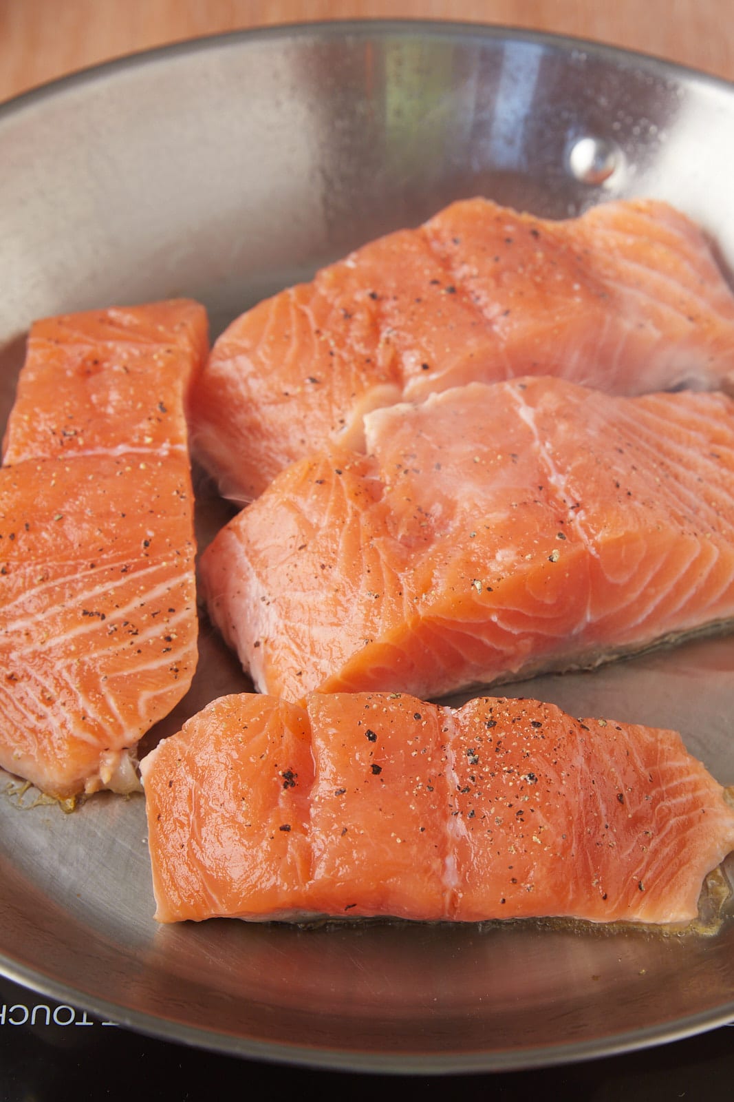 Raw salmon skin side down in a pan.