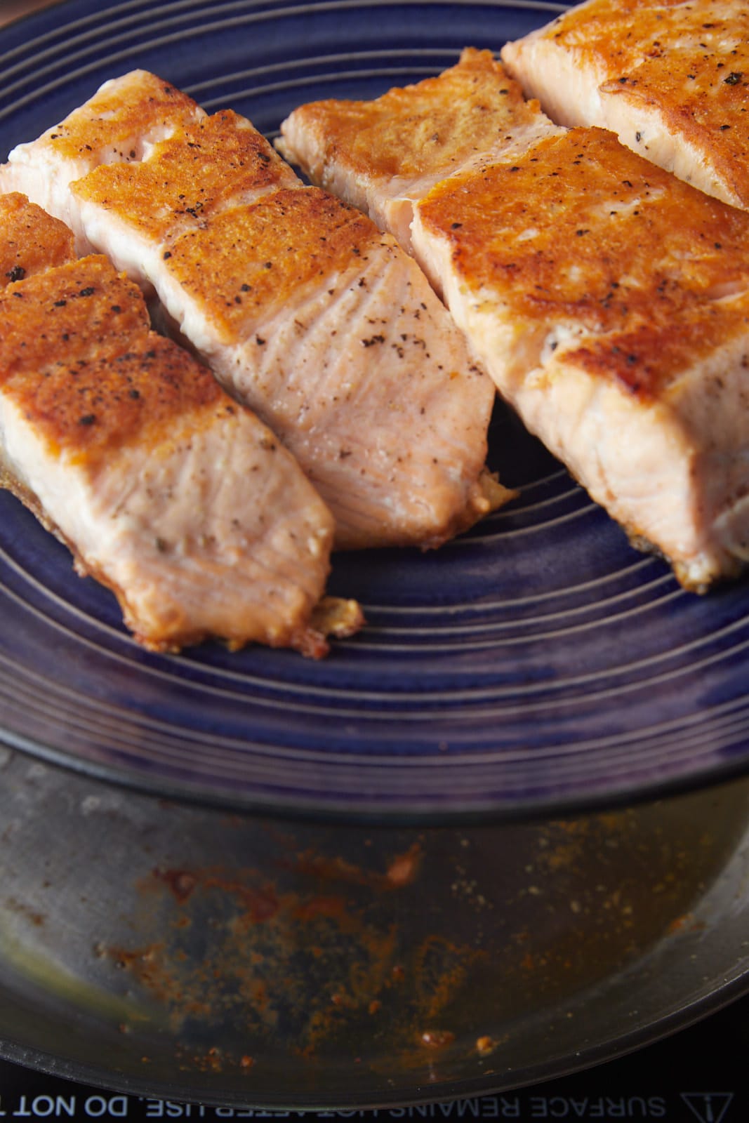 Four pieces of cooked salmon on a blue plate.