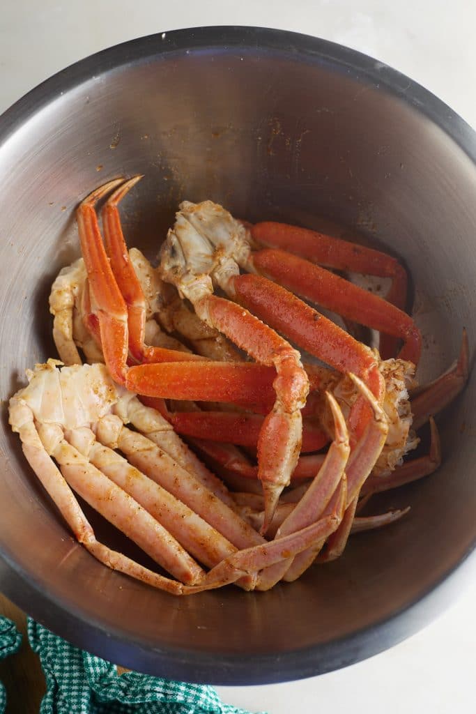 Crab legs with seasonings in a silver bowl.