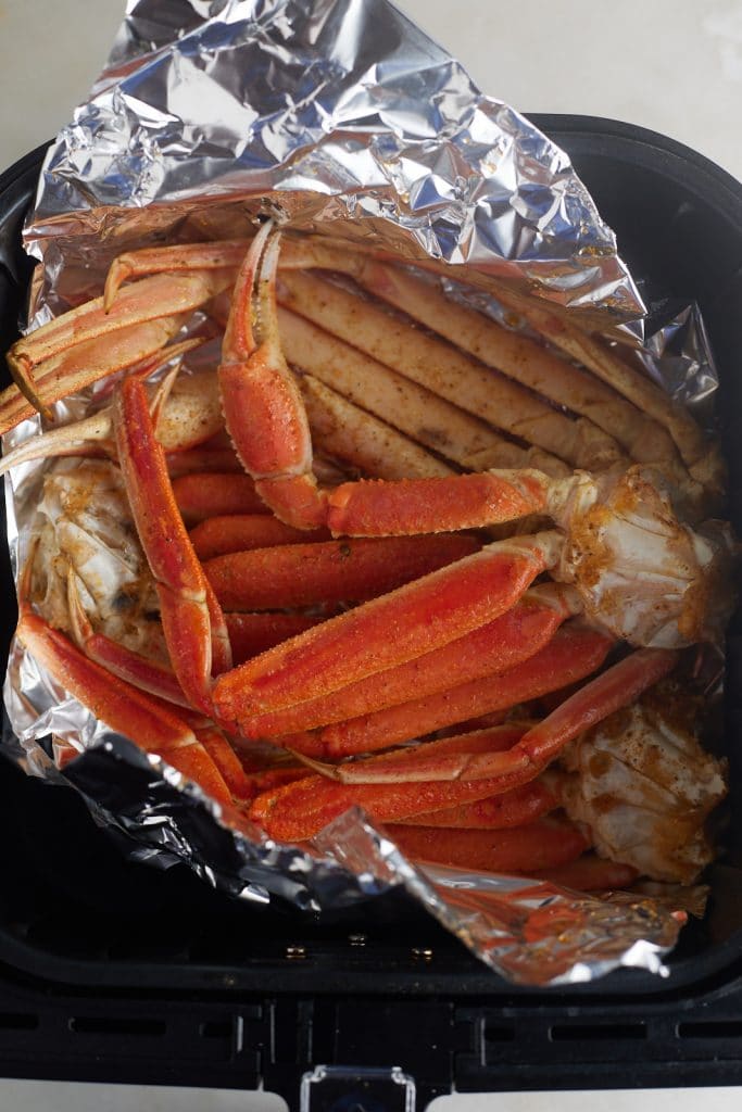 The cooked crab legs on foil in the air fryer basket.