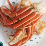 Air fryer crab legs on a white plate and garnished with herbs.