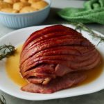 The glazed holiday ham served on a white plate.