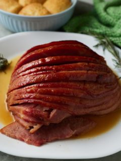 Sliced glazed ham served on a white plate ready to eat.