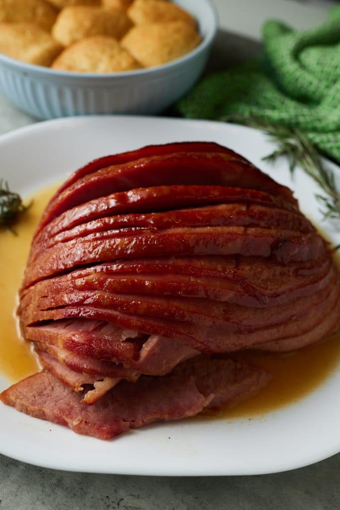 Sliced glazed ham served on a white plate ready to eat.