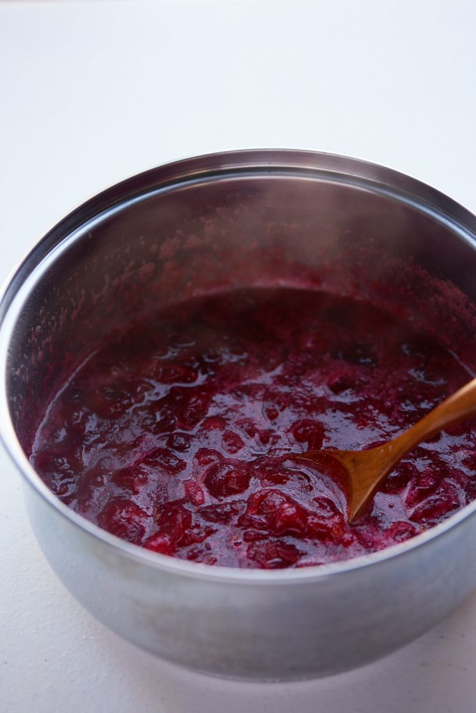The cranberry sauce in a pot with a wooden spoon ready to serve.